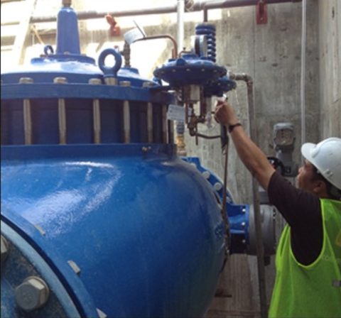 Homme portant un casque de protection et travaillant avec un réservoir sous pression.