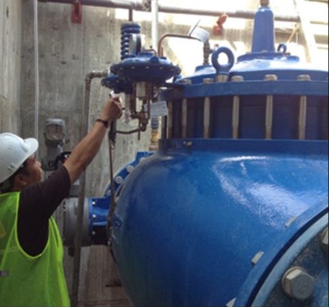 Man in a hard hat working with a pressurized tank.