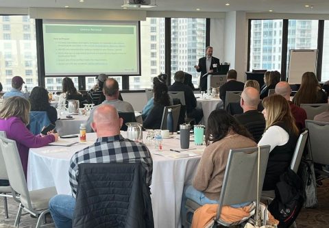 Participants assis à des tables écoutant un présentateur lors d'une session de l'atelier L’eau potable en Ontario - Norme de gestion de la qualité.
