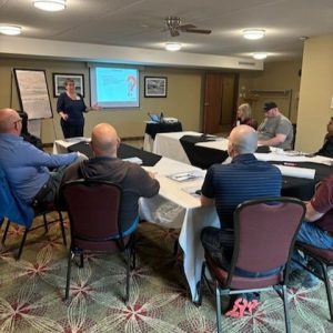 Un groupe de participants assis à des tables lors d'une présentation à l'atelier NGQEP 2024.